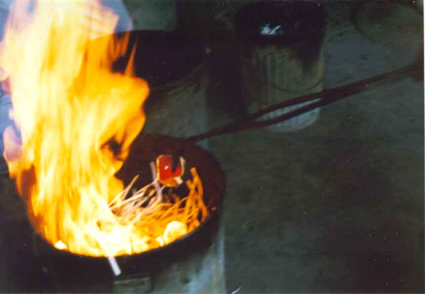 The pottery is being placed into a reduction chamber. Notice how the combustible material ignites